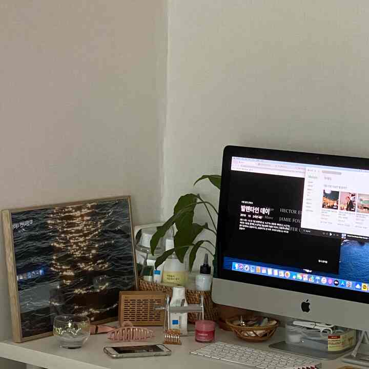 白を基調としたホームオフィス、机の上に額縁と植物が置かれたシンプルな作業空間