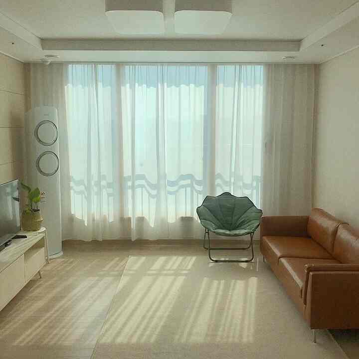 White-tone living room featuring brown sofa and green armchair with simple and open atmosphere