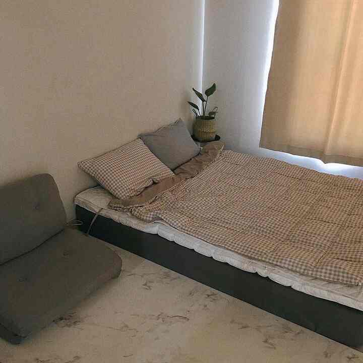 Beige and gray toned bedroom featuring a checkered blanket and a low sofa with a cozy atmosphere