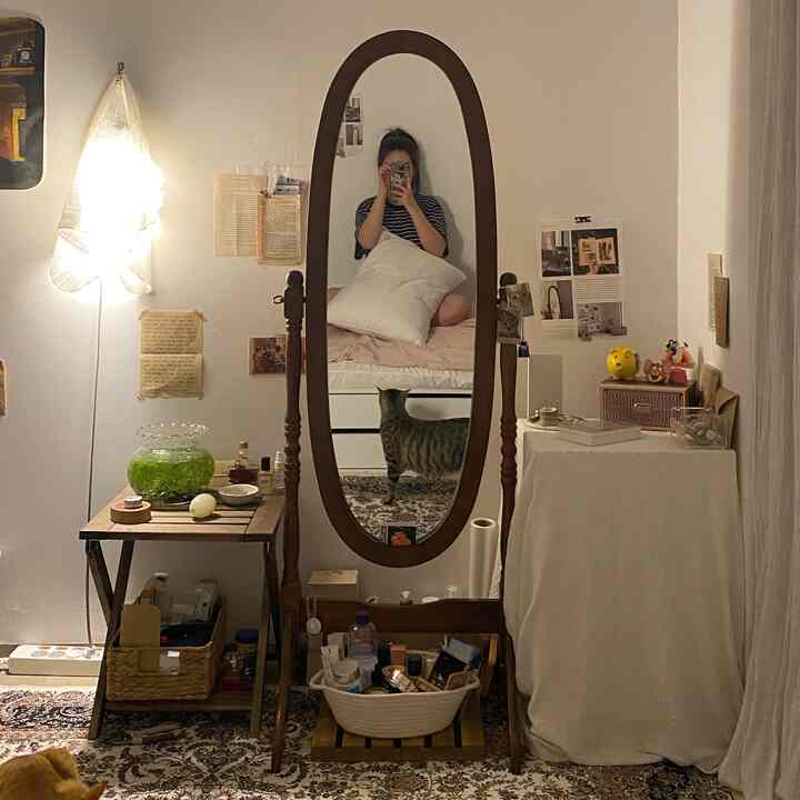 暖かいホワイトと木目調が基調の6畳の部屋、ヴィンテージラグと全身鏡、猫がいる居心地の良い個室