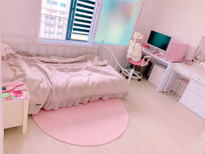 ピンク色調の寝室空間、一人用ベッドとドレッサー、パソコンデスクが配置されたシンプルでミニマルなインテリア