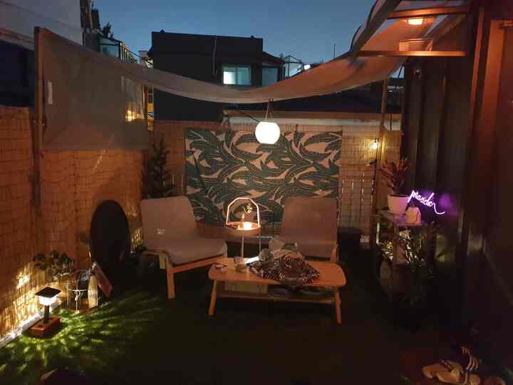 Cozy rooftop balcony space with natural wood furniture and neon sign under soft dusk lighting
