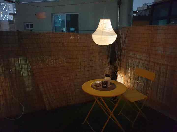 Warm beige-toned rooftop veranda featuring a yellow folding dining table and chair, creating a cozy cafe-style ambiance