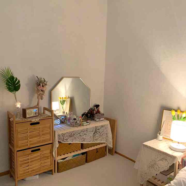 ナチュラルな木目調と白い壁の寝室の一角、レースをかけた化粧台と収納棚が温かみのある雰囲気を醸し出している