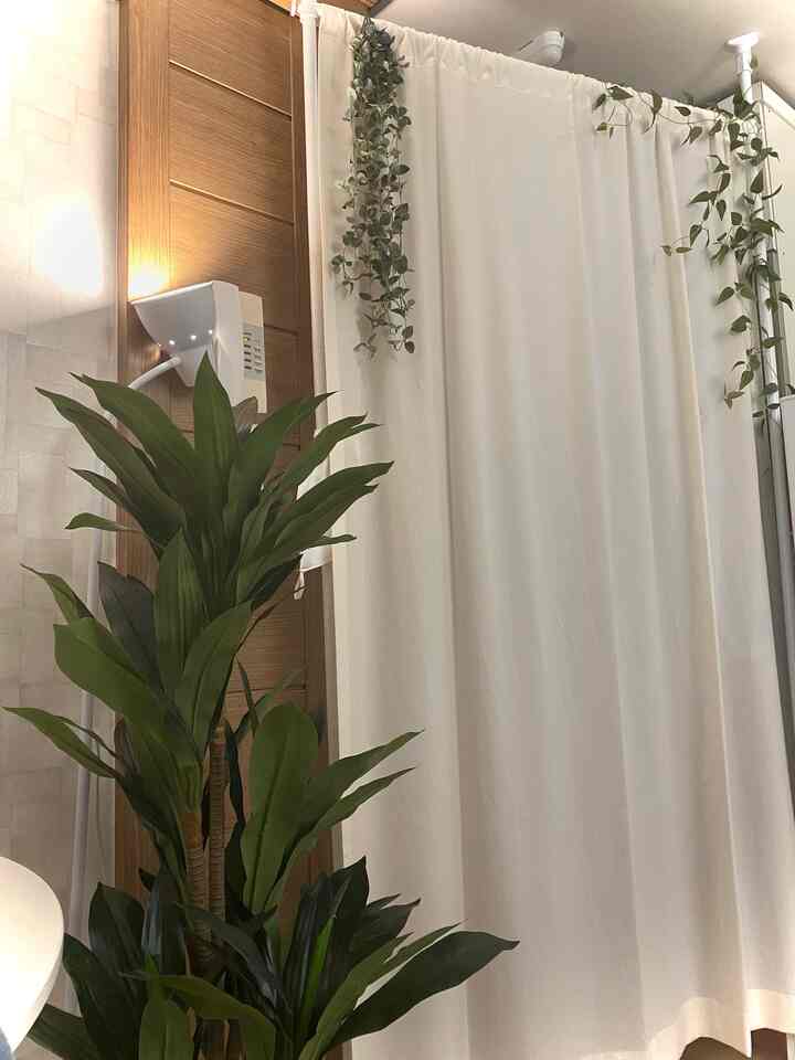 白いカーテンと木目調の壁があるキッチン空間、緑の植物がアクセントの自然な雰囲気のインテリア