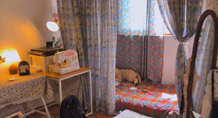 Natural-toned bedroom and home office space featuring floral patterned curtains and a small bed