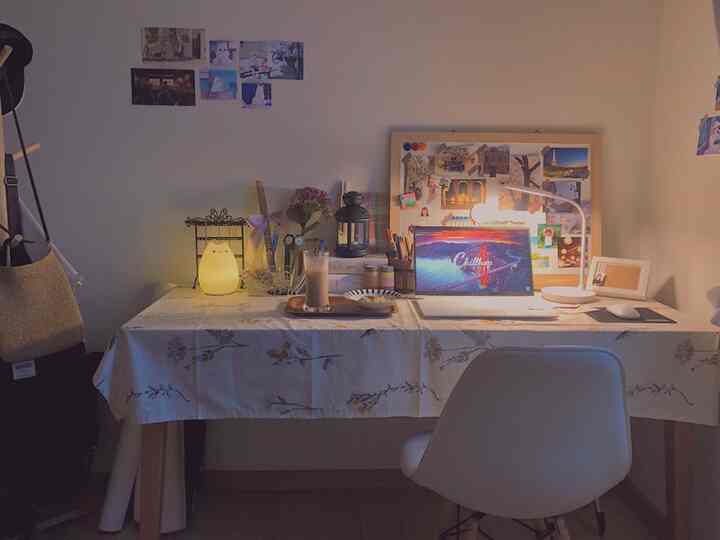 Cozy desk room in warm ivory and white tones featuring floral tablecloth, stand lamp, and mood light