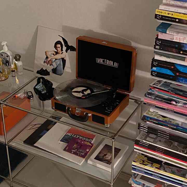 Neutral-toned wall with metal glass shelf featuring a vintage retro turntable and stacked books in a Nordic simple space