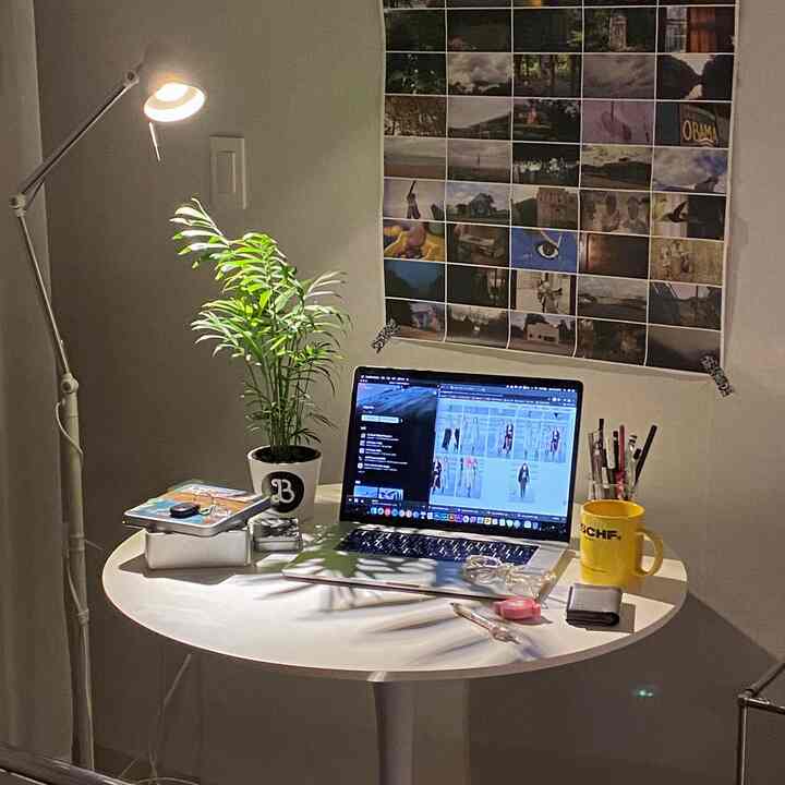 白を基調とした狭い部屋のホームオフィス、円形テーブルとフロアランプが配置されたシンプルな作業空間