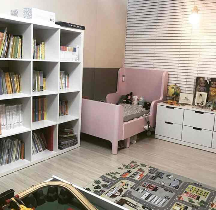 White and pink toned kids' room featuring a bookshelf and a toddler bed with a neat and organized atmosphere