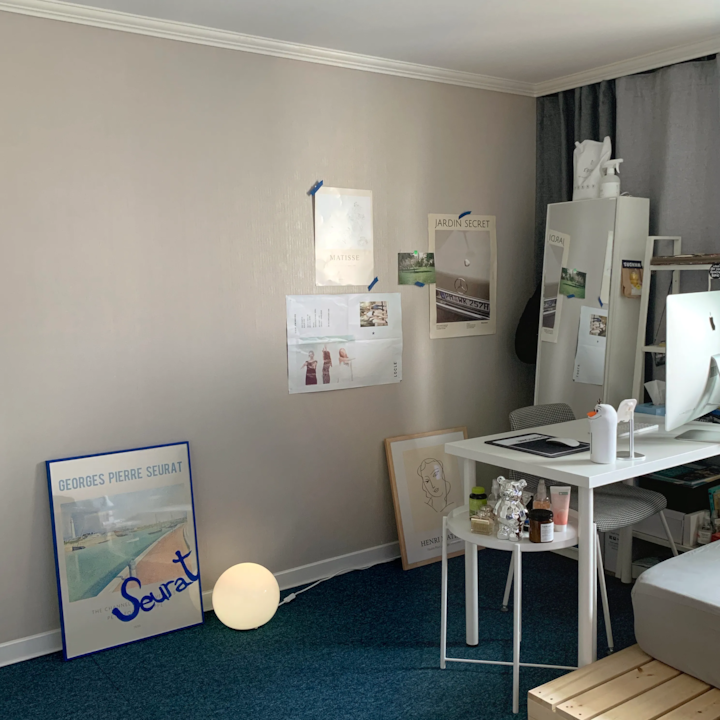 Small home office in gray and natural tones featuring a white desk and chair, multiple posters on the wall, creating a modern workspace