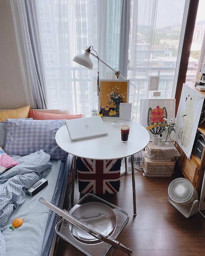 Bright white and natural-toned small living room featuring round table, transparent chair, and cozy sofa arrangement