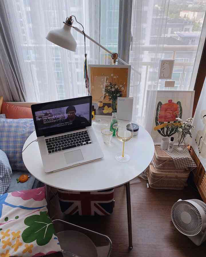 白とネイビーの色調のコンパクトなリビングルーム、丸いコーヒーテーブルとアームチェア、大きな窓と多様な小物が配置された雰囲気のある空間