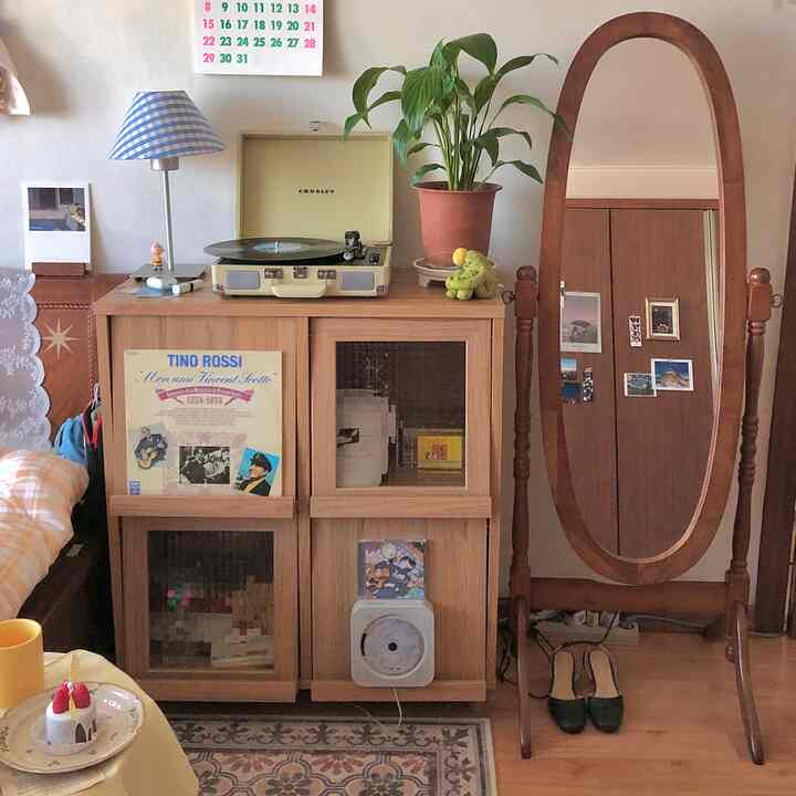 ブラウンの木目調が特徴的なリビング、全身鏡とヴィンテージの収納家具が配置された雰囲気のあるインテリア