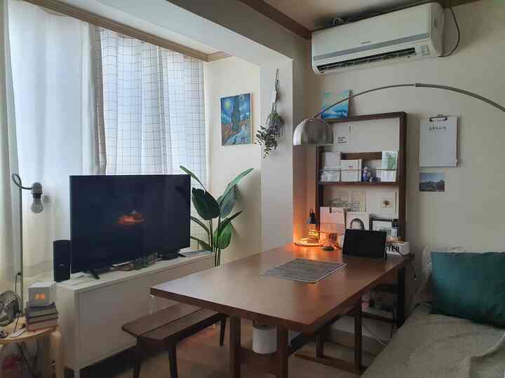 ホワイトとブラウンの色調が印象的な6坪のワンルーム、テレビ台とナチュラルな木製テーブル、ソファを配置した雰囲気のある空間