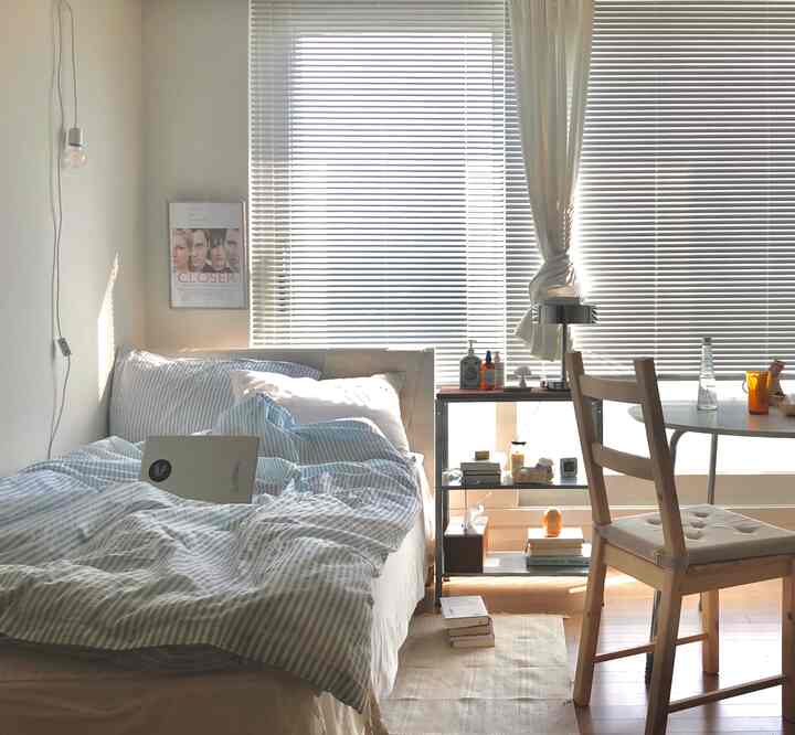 A white and natural color two-person bedroom featuring a bed and desk by the window, creating a cozy and functional space