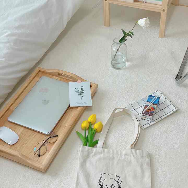 Bright and soft white-toned rug featuring a natural home office setup with a wooden tray and glass vase