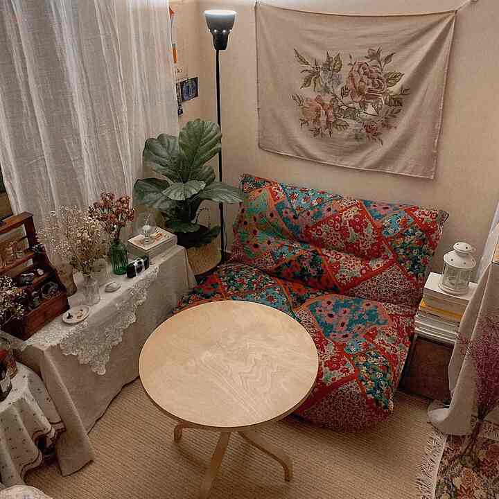 Light brown round table and vintage patterned sofa in a small single household room with a natural warm atmosphere