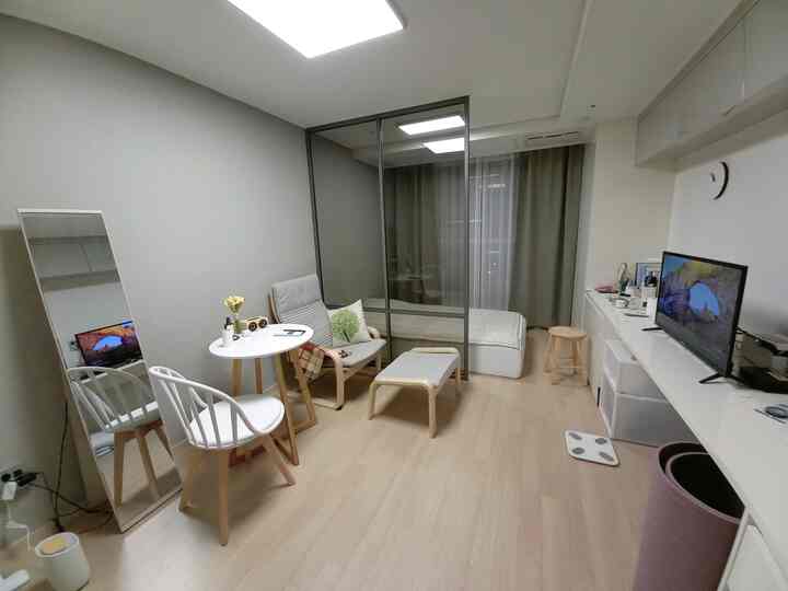 Beige wood tones and gray hues blend in a 1.5-room officetel space featuring a POÄNG armchair and bed, creating a cozy small studio apartment interior