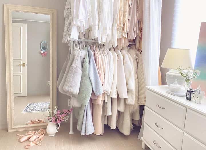 白とベージュの色調のウォークインクローゼット、中央にハンガーとドレッサーが配置され、落ち着いた清潔感のあるインテリア