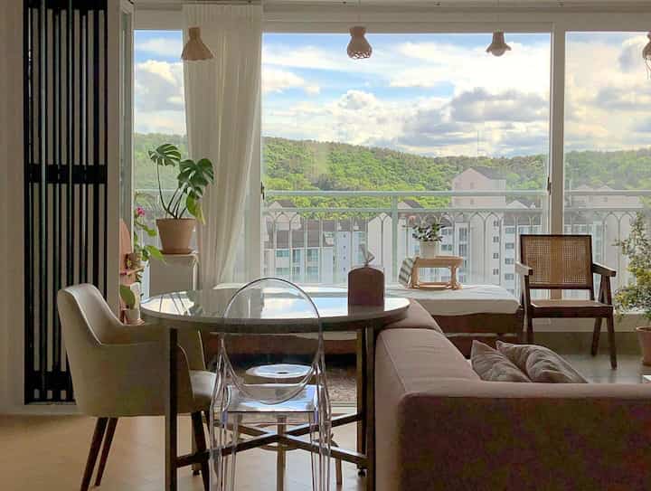 Natural tone living room featuring transparent furniture and large window with balcony, creating cozy atmosphere
