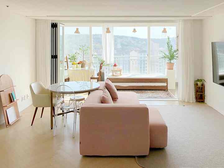 Bright light brown and white living and dining room featuring natural furniture and plants in a cozy space