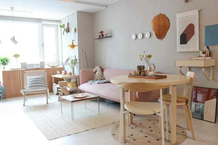A living room with wood tones and bright natural hues, featuring a pink sofa and wooden tables creating a cozy atmosphere