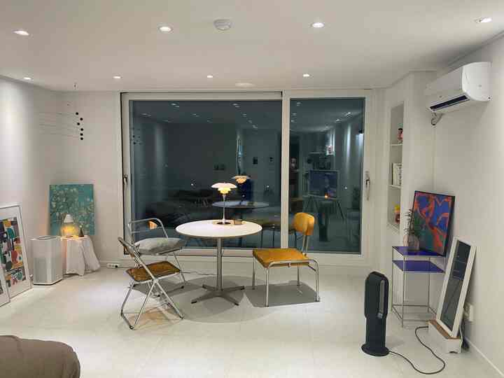 White-toned veranda featuring a round dining table and yellow chairs, simple and bright home cafe workspace