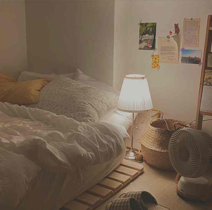 White and wood tone bedroom featuring a bed, lamp, and rattan basket creating a cozy atmosphere