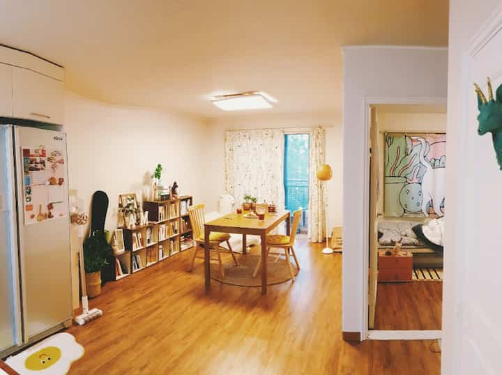 Yellow and beige-toned living room featuring a wood dining table and rattan accessories creating a warm atmosphere