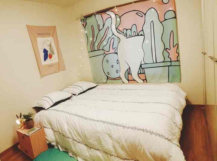 A white and wood-tone bedroom for a single household featuring a large bed, fabric posters, and a mini vanity creating a cozy atmosphere