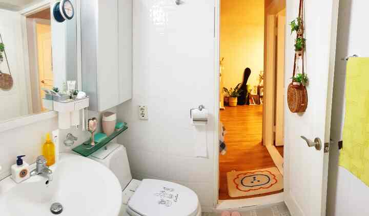 White-tiled small bathroom with bathroom fixtures and a bath mat placed by the door, neat and compact space