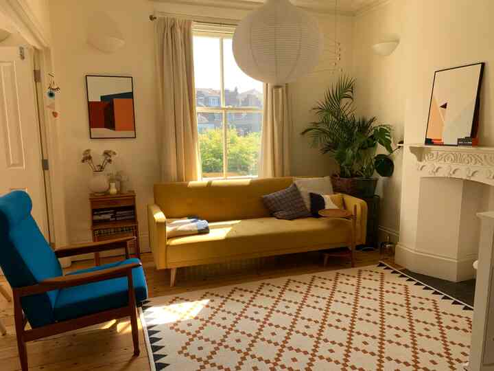 明るいベージュの壁と木製の床、黄色のソファと青いアームチェアが配置された北欧風リビング