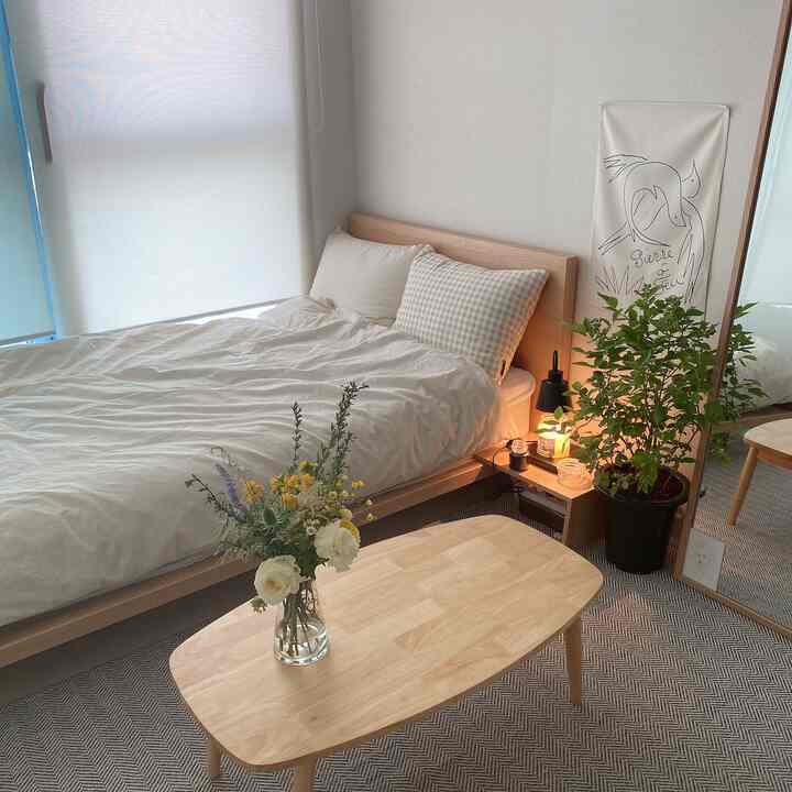 A cozy single household bedroom featuring white and wood tones, with minimalist and natural decor elements