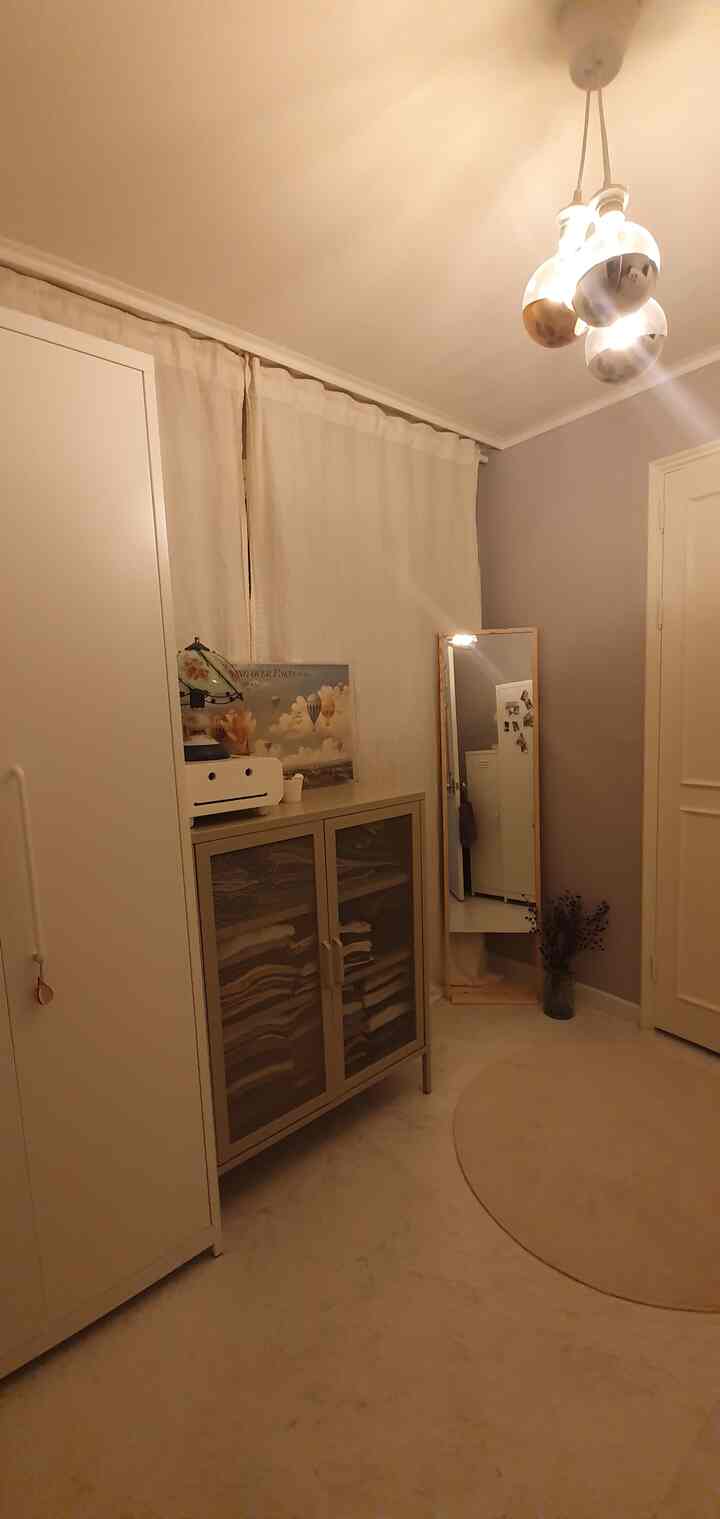 Warm beige and white toned entrance space featuring storage cabinets and a full-length mirror with a cozy atmosphere