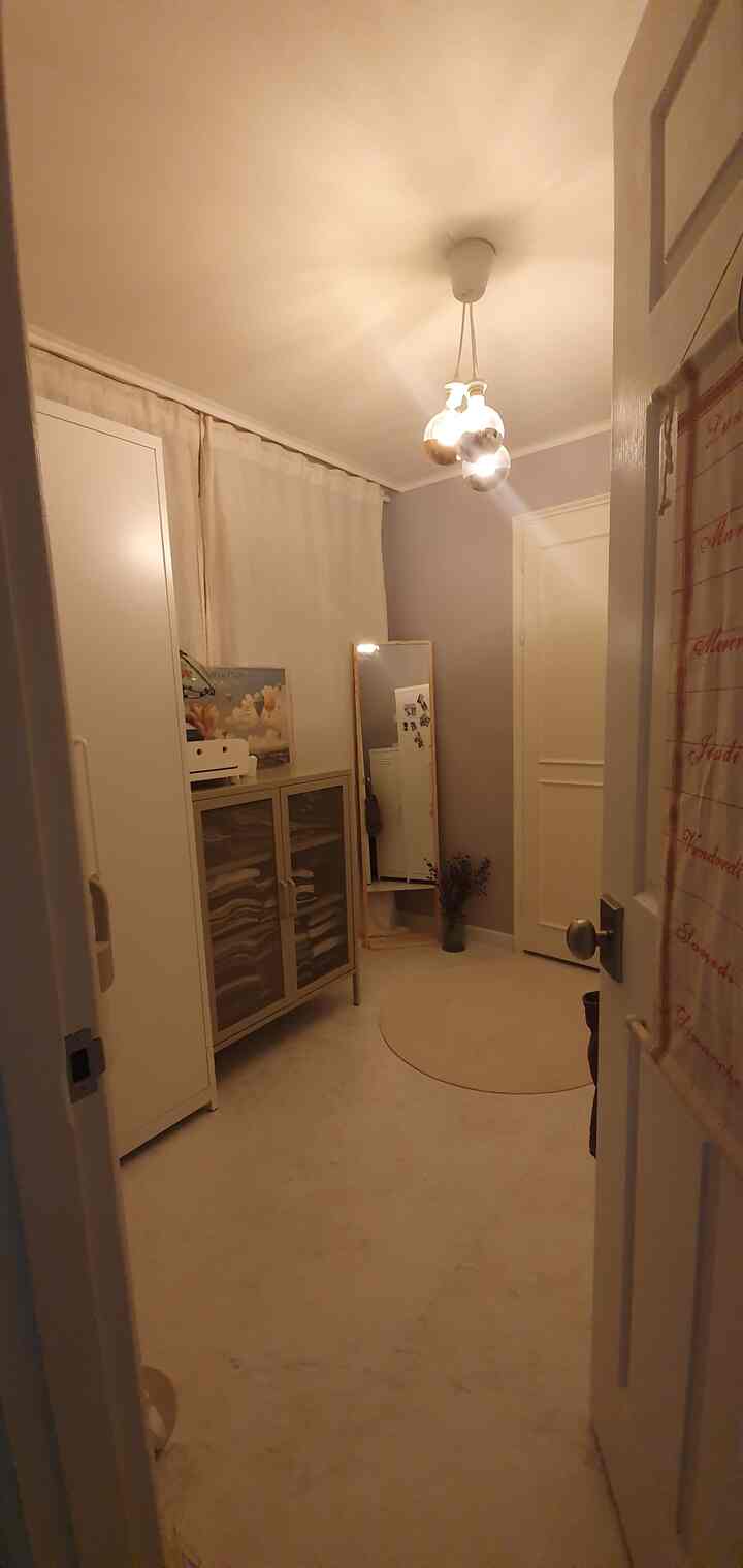 Narrow entrance space in white and light gray tones featuring cabinets and a full-length mirror with neat storage layout