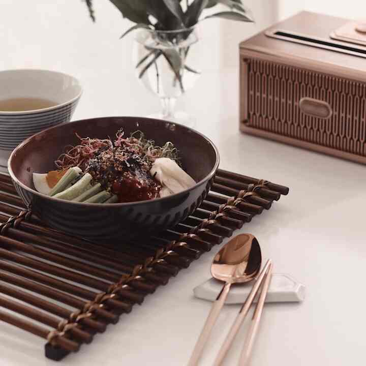 White table with wood tone tray, brown bowl, and rose gold cutlery creating a natural dining setting