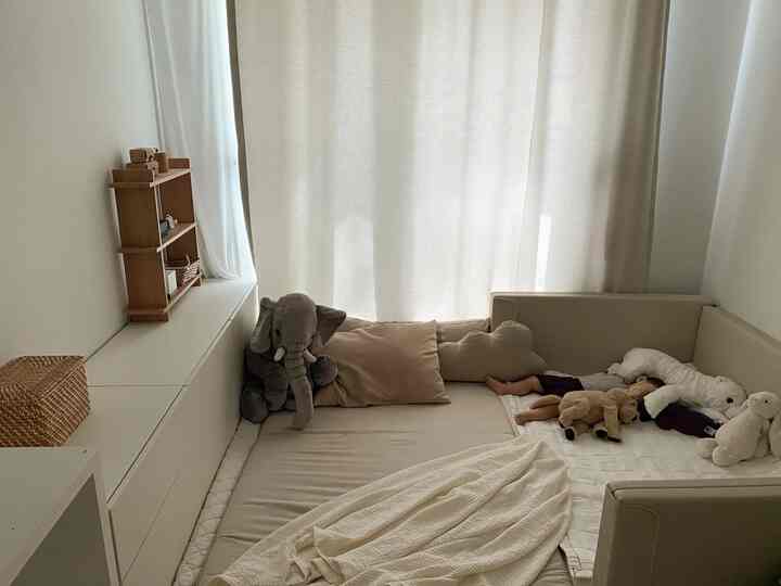 ベージュとアイボリーのトーンの小さな赤ちゃん用寝室、バンパーベッドと収納棚が配置された雰囲気のある空間