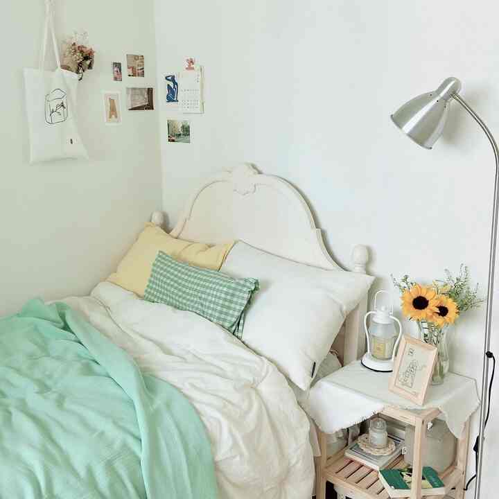 白と木目調の寝室、自然な寝具とフロアランプが配置された落ち着いた雰囲気のインテリア