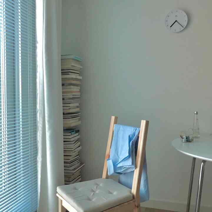 Bright natural-tone small room with wooden chair, round table, and blinds showcasing simple Nordic style interior