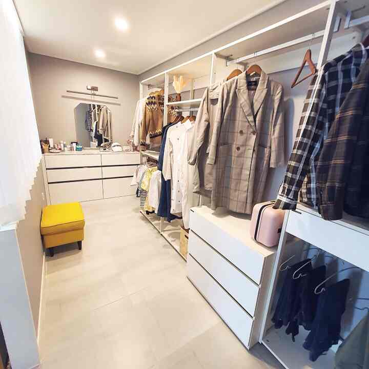 White and brown toned walk-in closet featuring clothes hangers and dresser, neat and spacious interior
