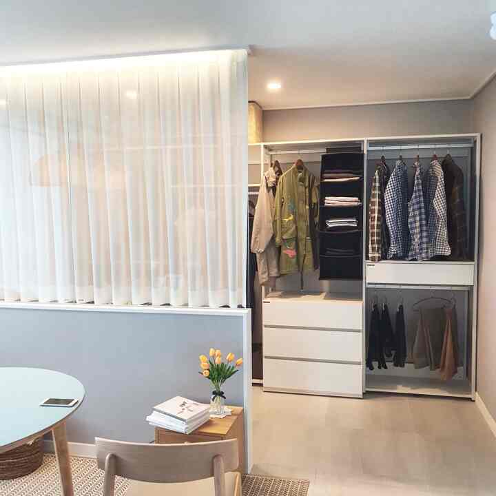 White and wood-tone walk-in closet with curtains creating an emotional cozy space