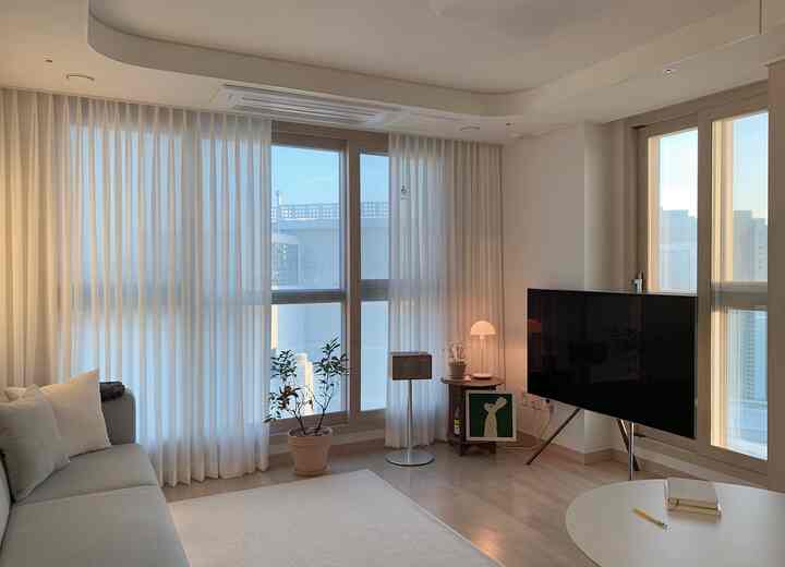Natural modern living room in white and wood tones, featuring a simple sofa and Elenaheim curtains with bright, spacious atmosphere