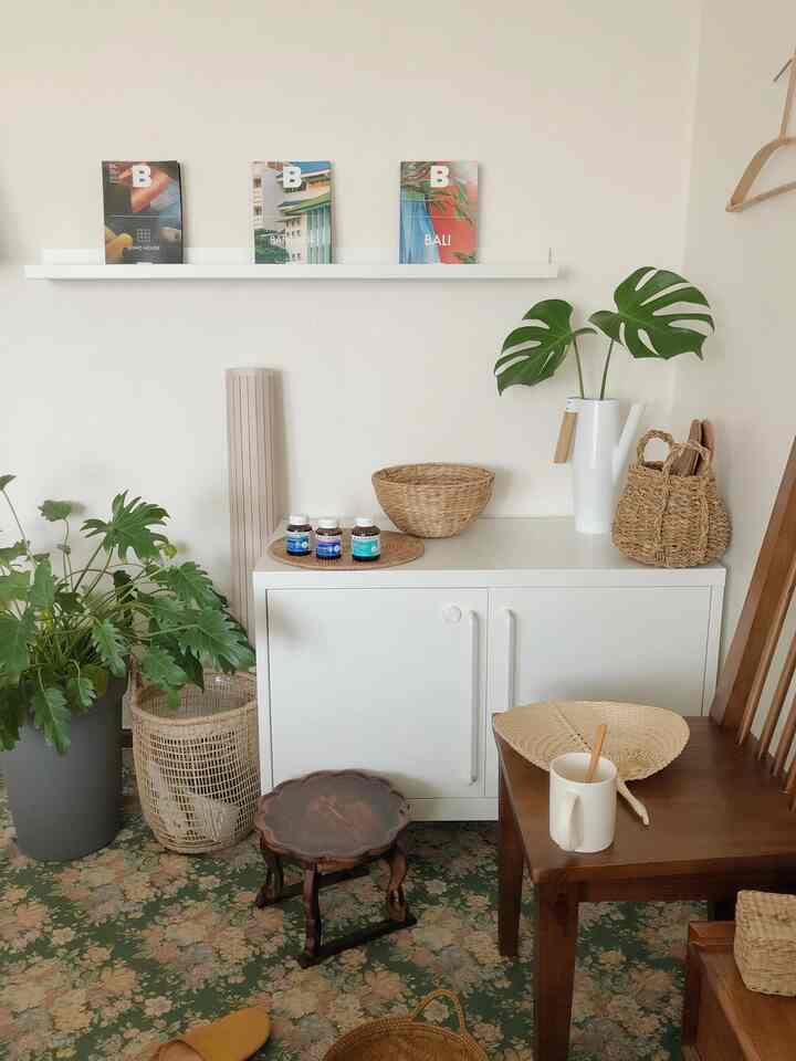 Natural and cozy interior space with white and brown tones featuring a cabinet, dining chair, plants, and woven decor elements
