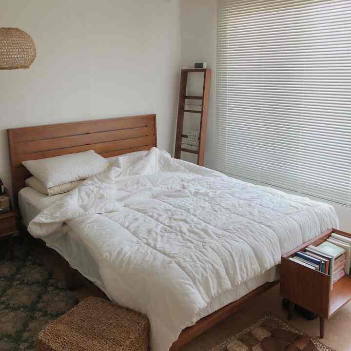 White and wood tone bedroom featuring white blinds and a wooden bed with a cozy atmosphere