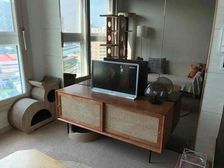 ナチュラルな茶色調のリビング、木製のテレビ台とキャットスクラッチャーが配置された落ち着いた空間