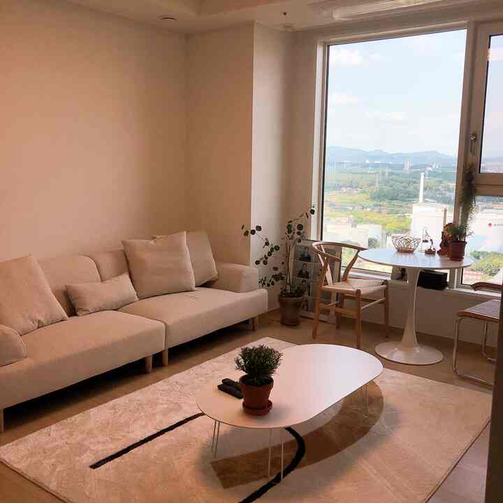 Beige-toned living room featuring a beige sofa and round dining table by the window, creating a cozy space