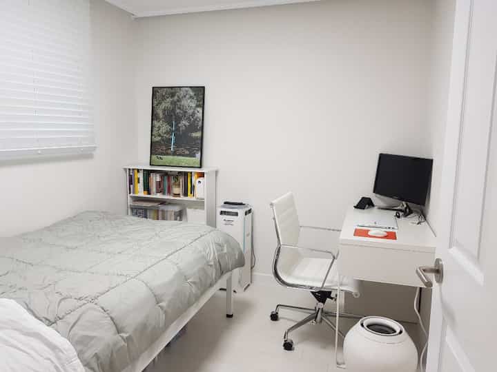 White minimal bedroom and study room featuring a bed, desk, and office chair in a clean layout