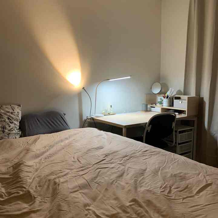 Beige and white toned bedroom-study space in a compact studio apartment, showcasing a cozy and natural atmosphere