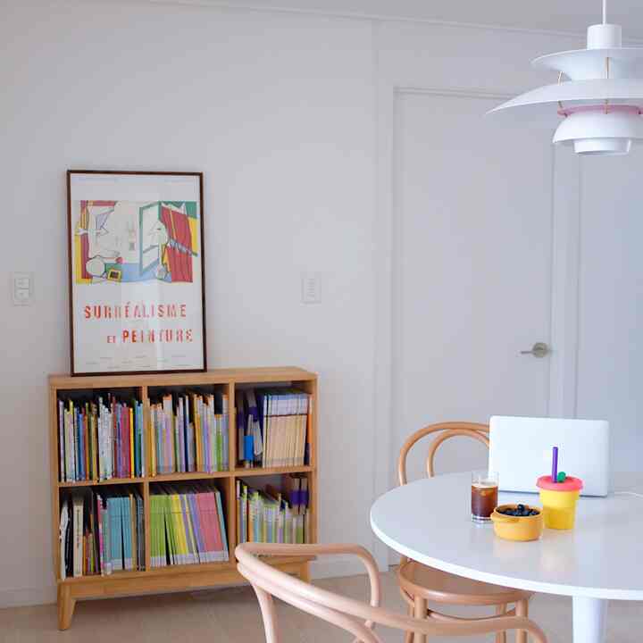 White and wood-toned dining room featuring a round dining table and bookshelf creating a cozy atmosphere
